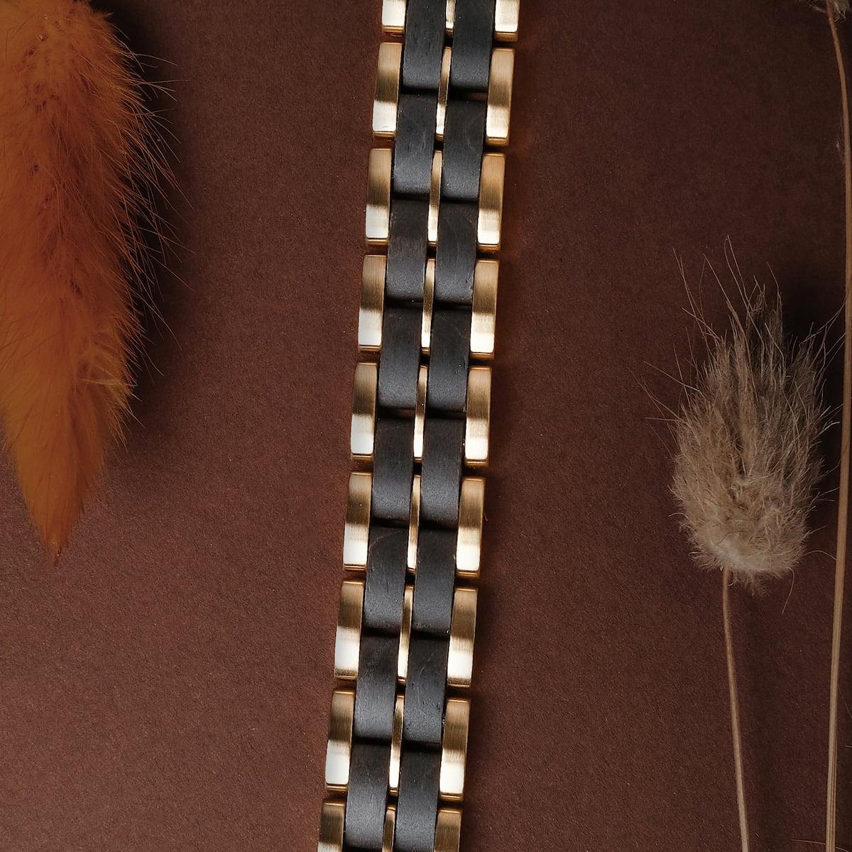 "Kanon" bracelet, featuring a sleek black maple and gold design, elegantly displayed with a natural backdrop.