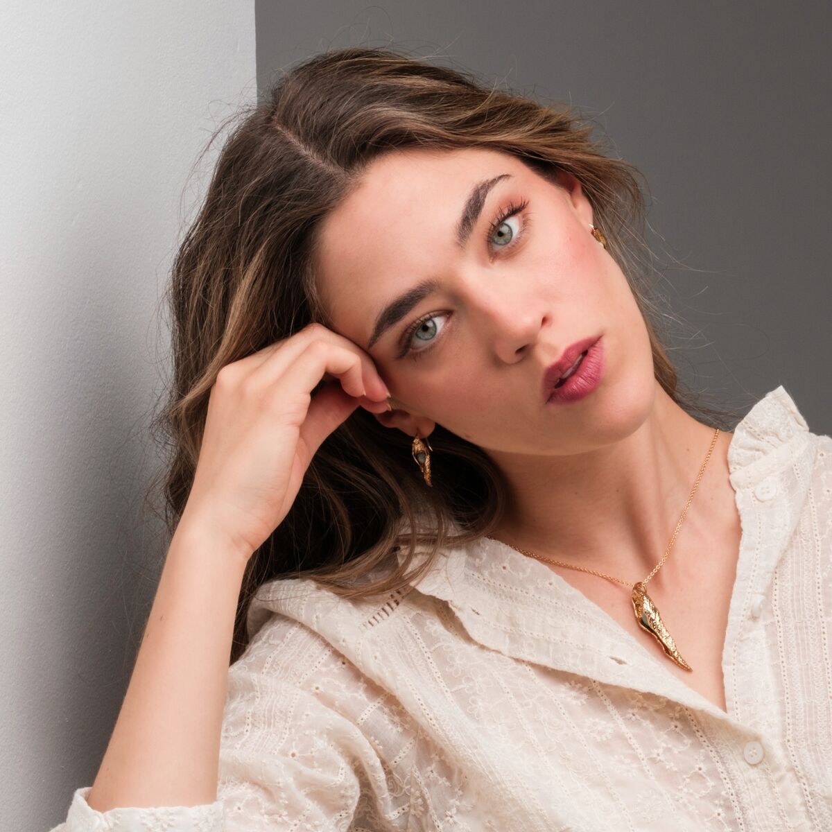 "Chalice Necklace" necklace featuring a gold and amazonite design, worn elegantly with a stylish white blouse.