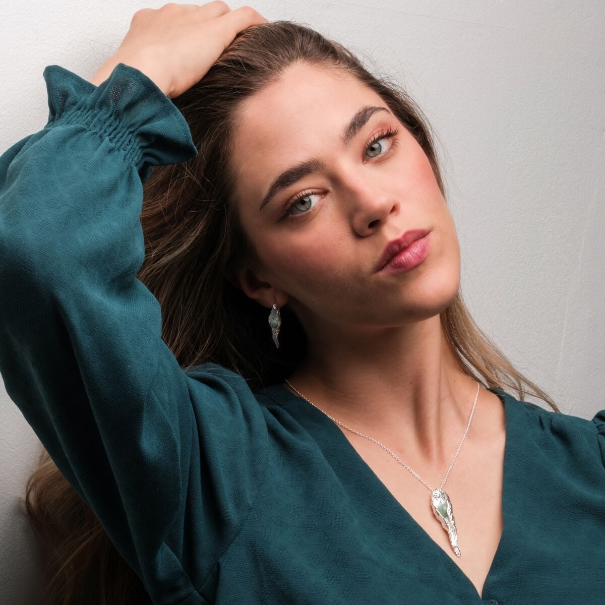 "Chalice Collana", una collana elegante con un set in pietra amaranita in argento, elegantemente indossato da un modello in un top teal.