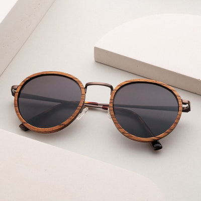"The Loving" sunglasses feature a round zebrawood frame and antique copper accents for a stylish, modern look.