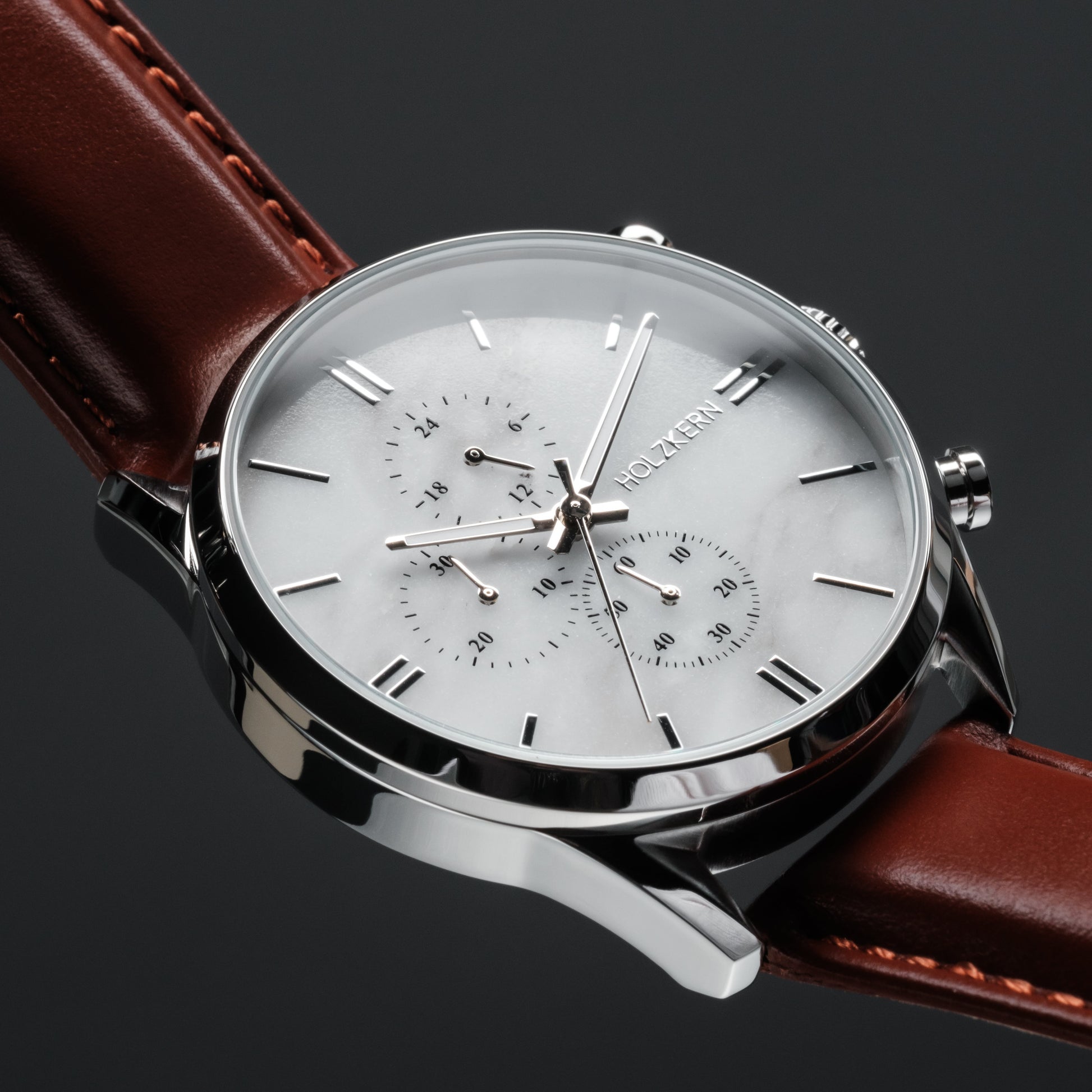 "Melodical", un orologio da polso in marmo e argento, caratterizzato da un design elegante con cinturino in pelle marrone.