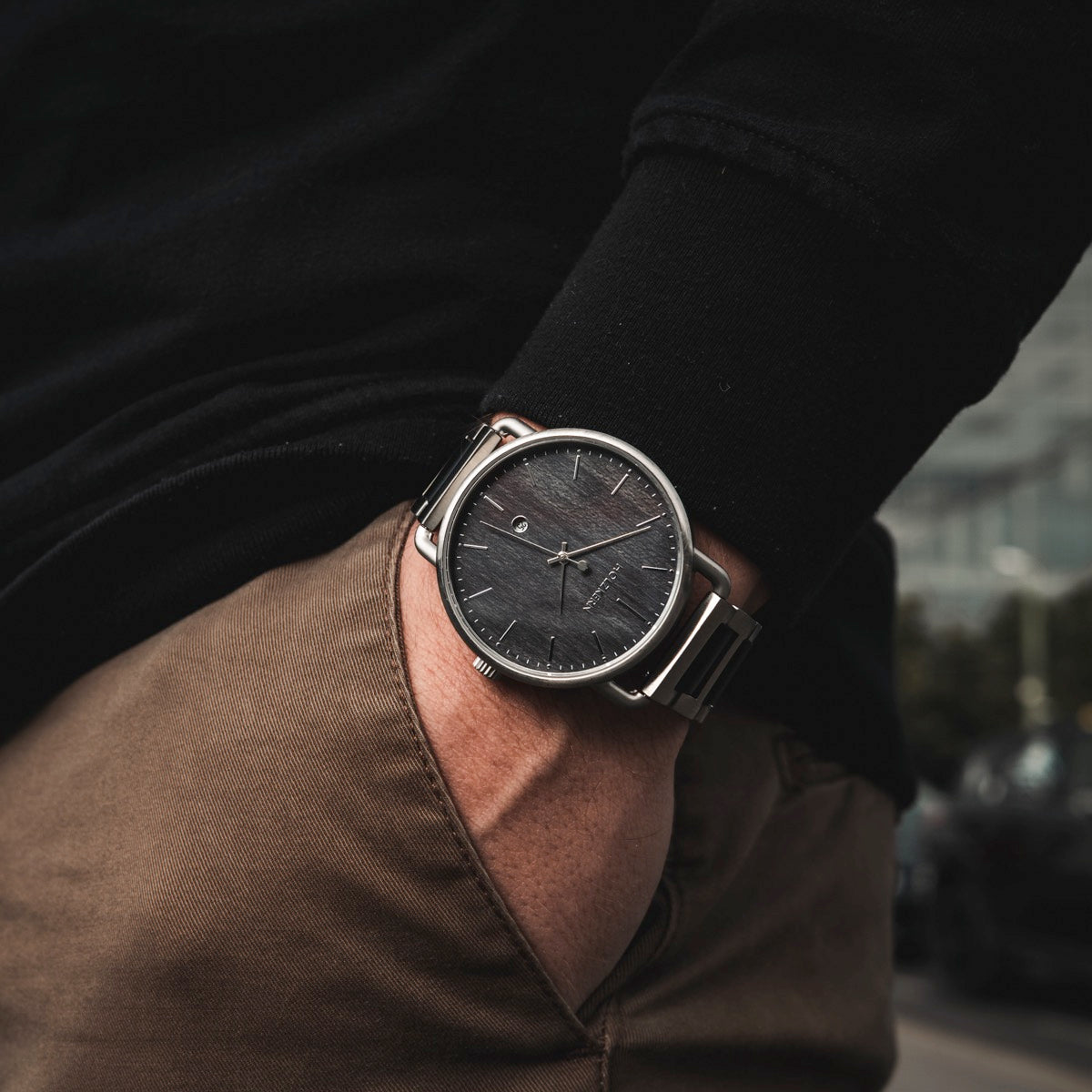 "Odaiba" orologio con un elegante quadrante nero e cassa in argento, indossato con abbigliamento casual per un look moderno.