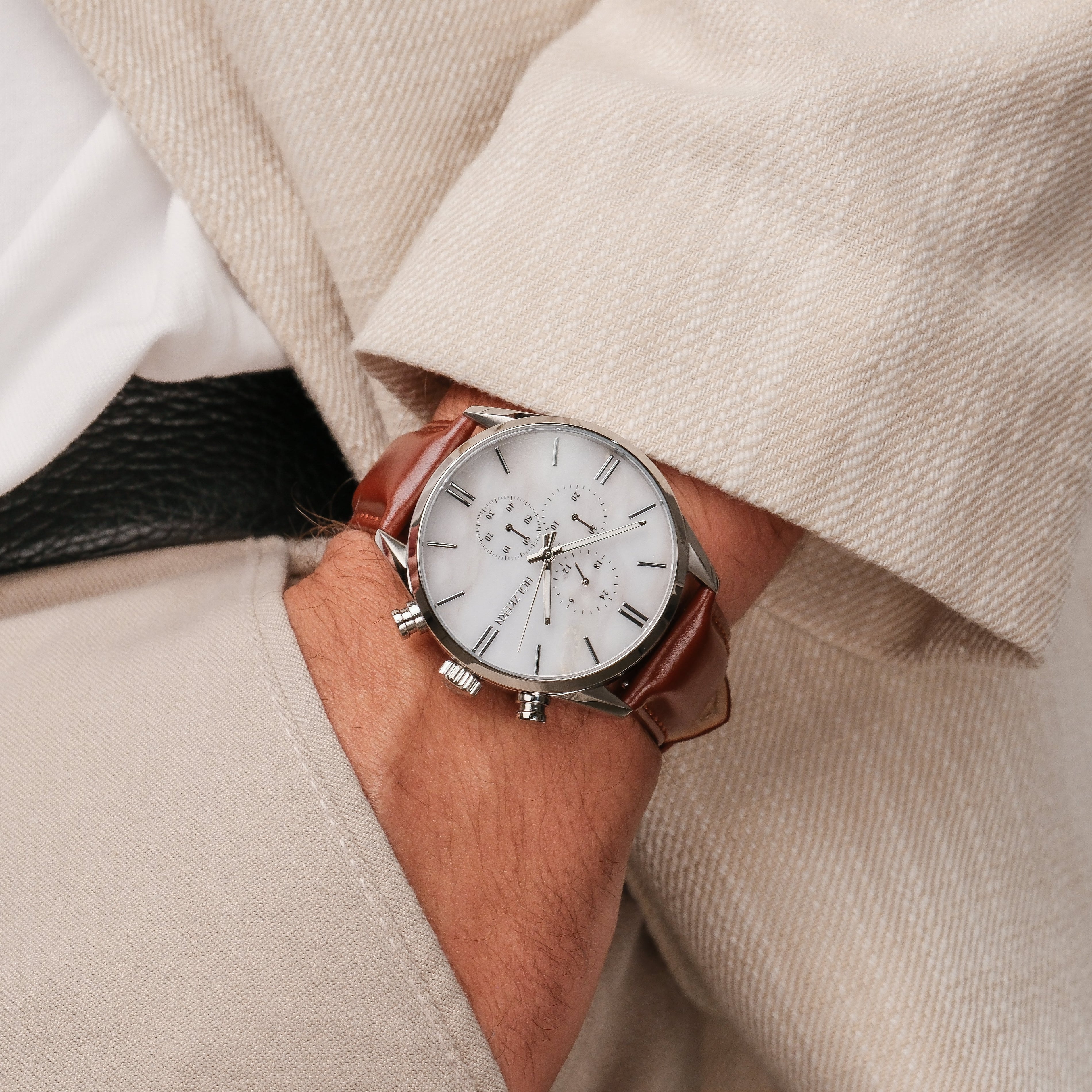 "Melodical" watch featuring a marble dial with silver accents and a brown leather strap, worn on the wrist.