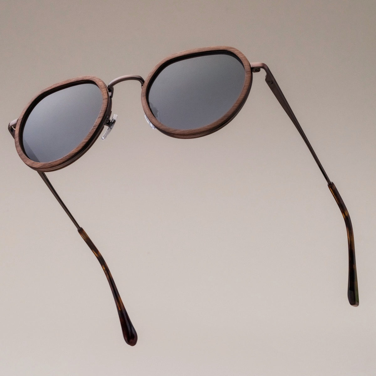 "The Wanderer", occhiali da sole con cornice in noce e accenti in bronzo, caratterizzati da un design elegante.