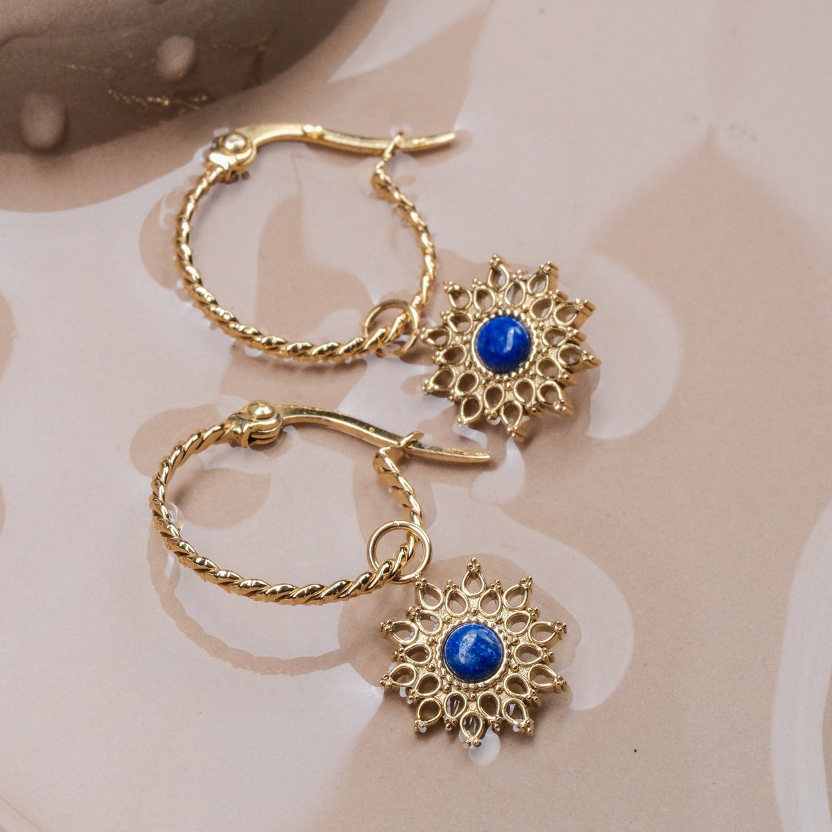 Orecchini Suncatcher, caratterizzati da un design intricato in oro con lapis lazuli center, trasudano uno stile elegante e radioso.