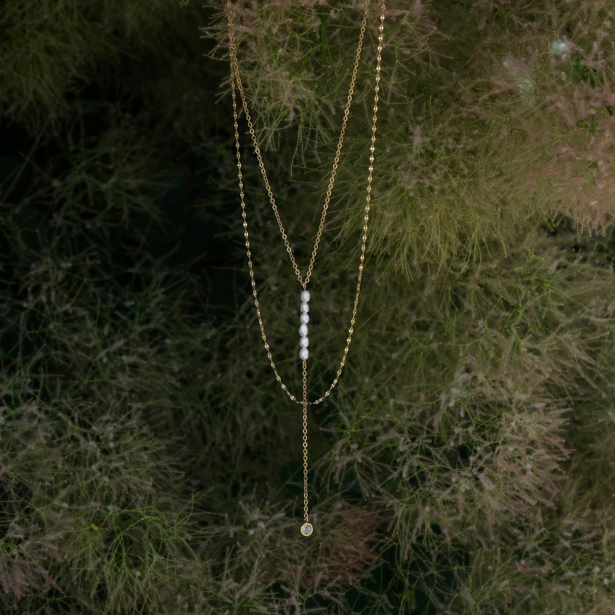 Collana "Collana di estate" con un design delicato perla e zirconi, ambientata su uno sfondo naturale per un aspetto elegante.