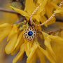 Collana "Suncatcher" con ciondolo in oro e lapis lazuli, in stile contro fiori gialli brillanti.