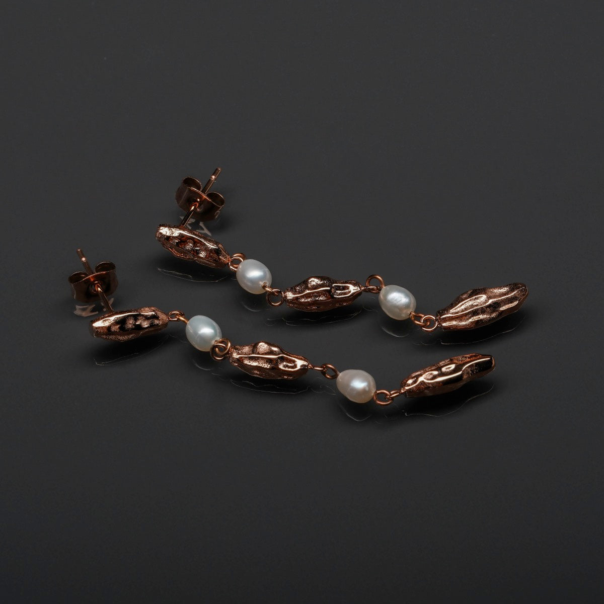 "Summersweet Earrings I elegant earrings featuring pearls and rose gold details on a sleek black background."