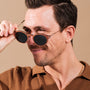 Occhiali da sole "The Maverick", caratterizzati da un design elegante in legno padouk e rame, indossati con un sorriso sicuro.