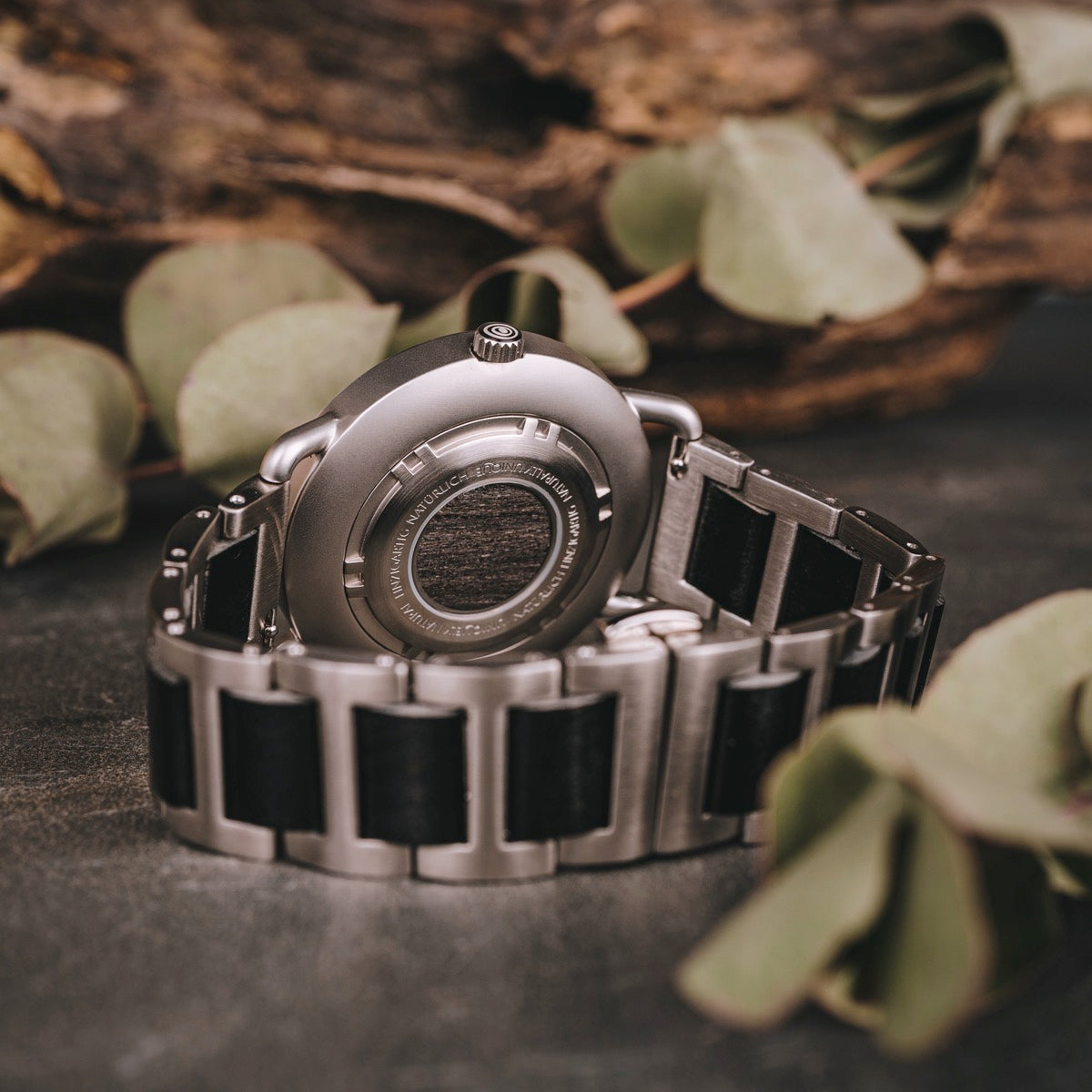 Orologio "Odaiba" con disegno acero/maple, caratterizzato da un'estetica metallica e legno in un ambiente naturale.