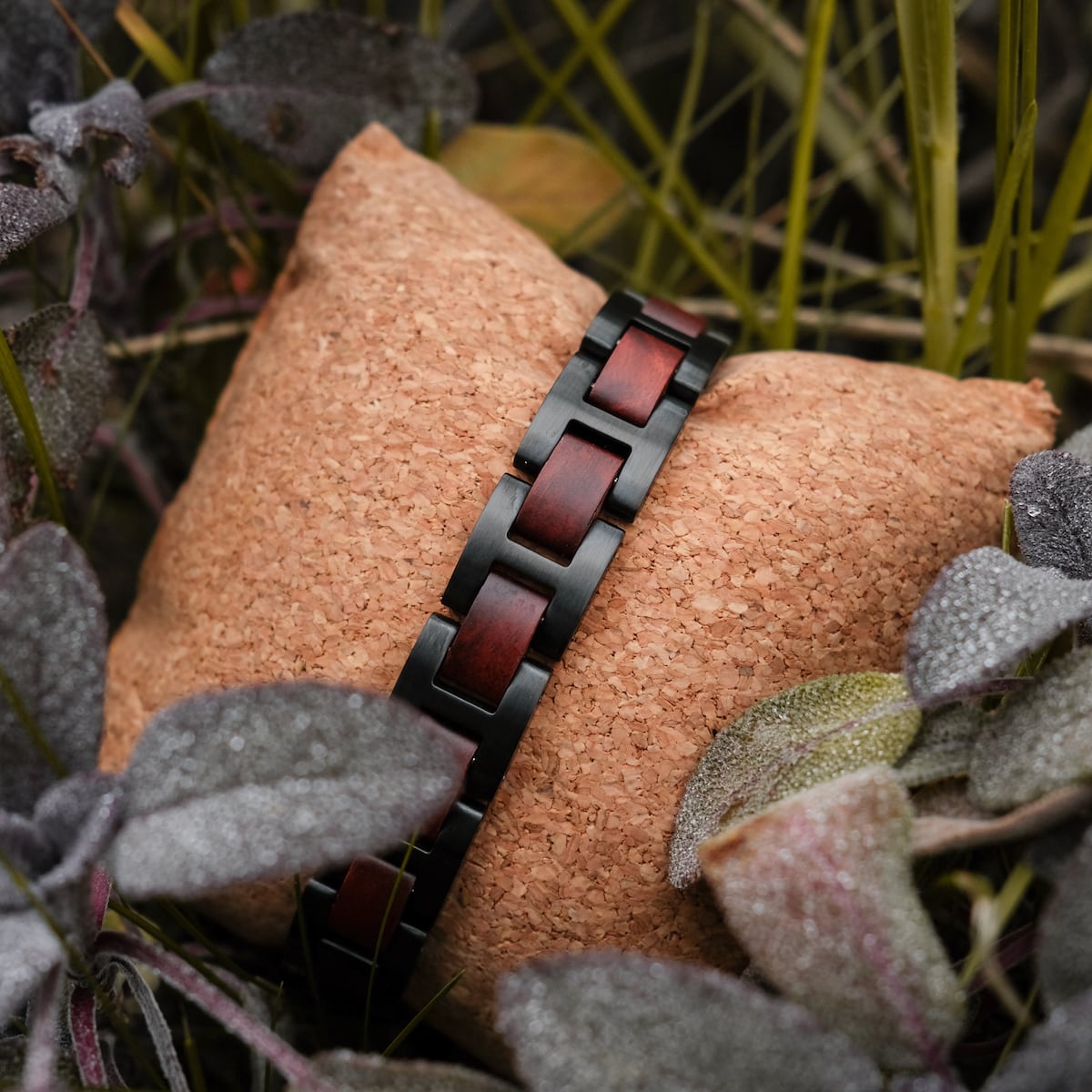 "Acoustic" bracelet featuring a sleek padauk and black design, elegantly displayed on a textured cushion.