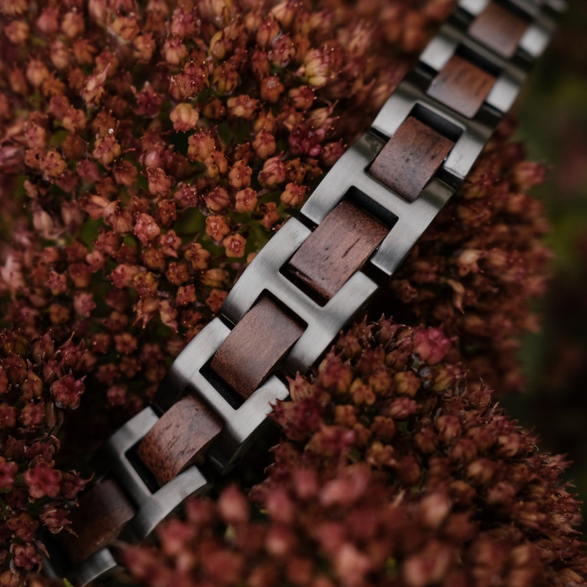 "Acoustic", a stylish bracelet featuring walnut and grey metal links among red flowers.