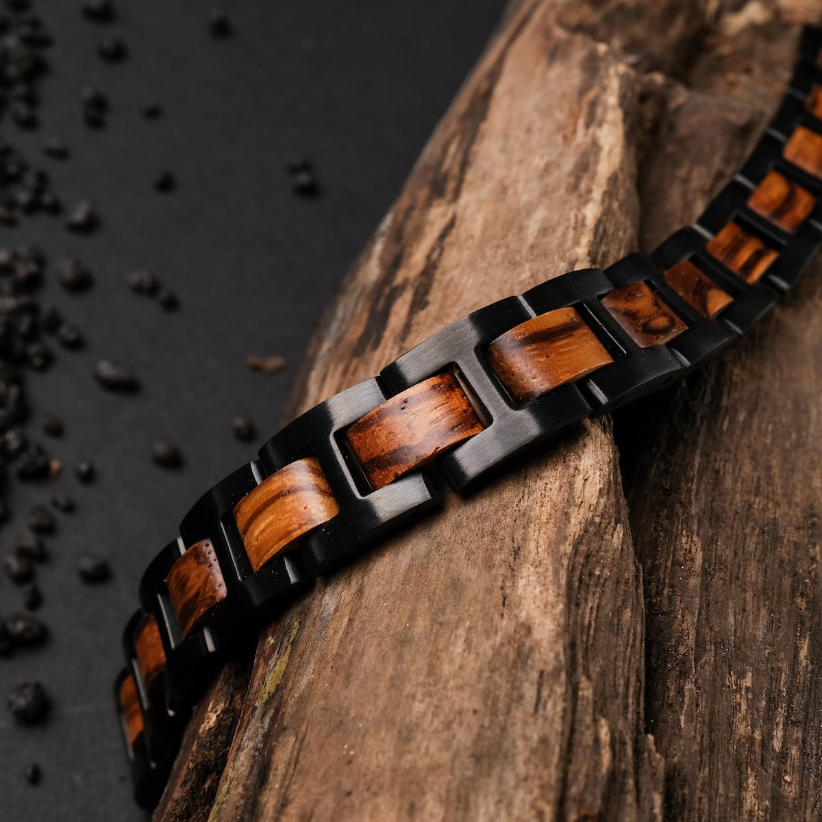 "Acoustic", un elegante bracciale con zebrawood e materiali neri, elegantemente esposto su una superficie in legno rustico.