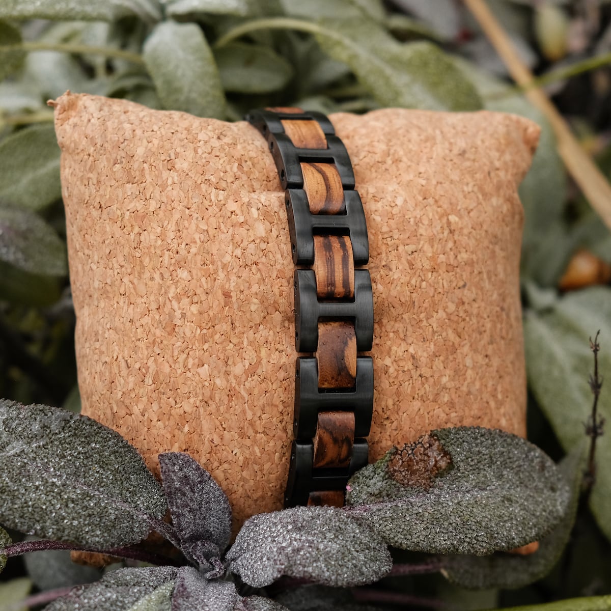 Bracciale "acoustico" con zebrawood e collegamenti neri in un ambiente naturale.
