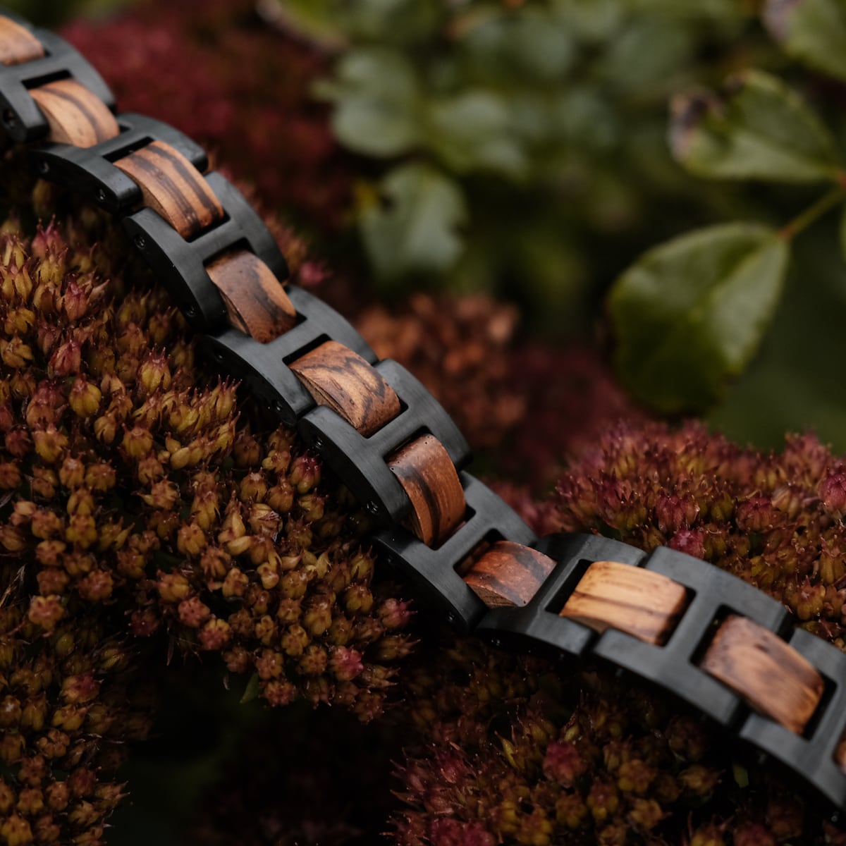 Bracciale "acoustico" realizzato in zebra di legno e materiale nero, che mostra un contrasto naturale ed elegante.
