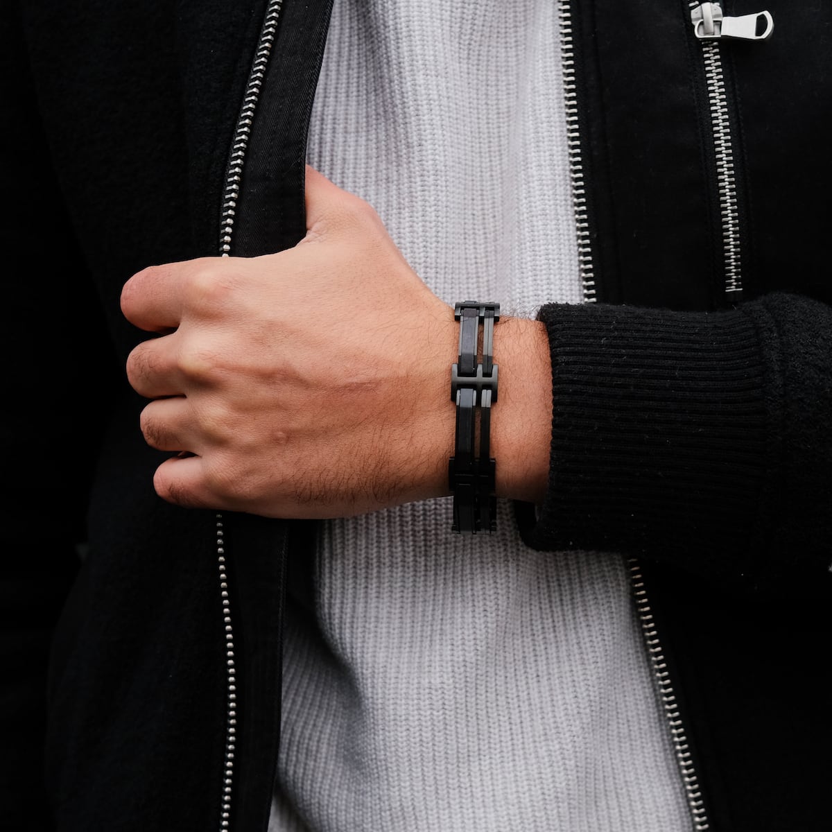 "Staccato", un elegante bracciale con un mix di acero e materiali neri, indossato con abbigliamento casual.