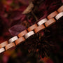 "Rondo" bracelet in cherry and rose gold, elegantly designed for a warm, natural aesthetic against a floral backdrop.