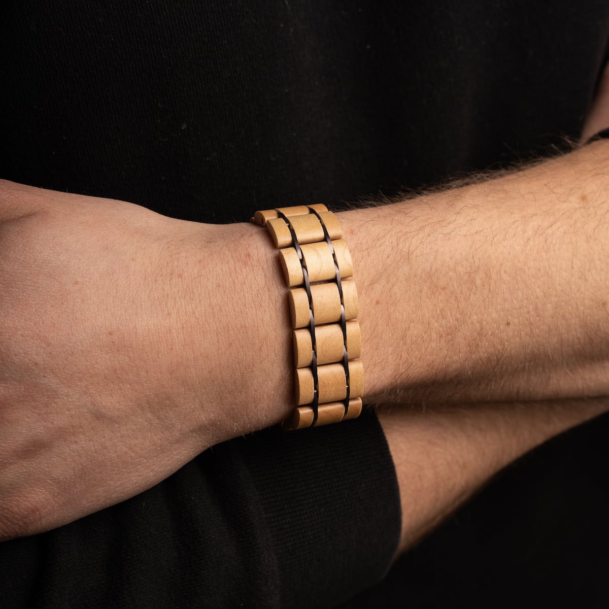 Bracciale in legno "Grandezza" in acero e viola scuro, che mostra un design elegante e moderno sul polso.