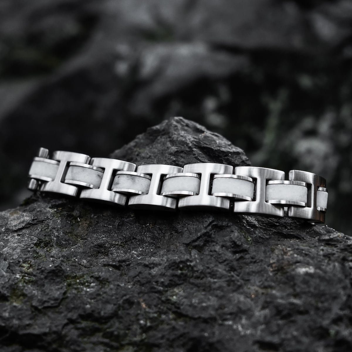 "Forte" bracelet in a marble and silver design, showcasing a sleek and modern style on a rugged rock background.