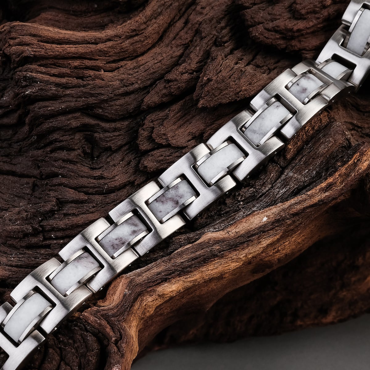 "Forte" bracelet in marble and silver, showcasing a modern, geometric link design against a textured wooden background.