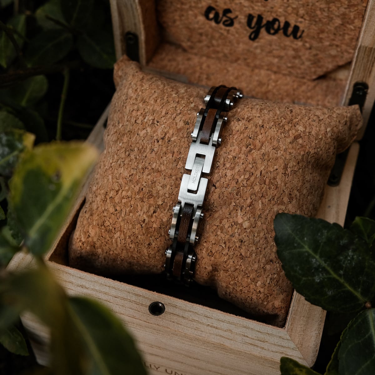 "Allegro" bracelet featuring walnut and silver materials, presented on a cork cushion in a rustic wooden box.