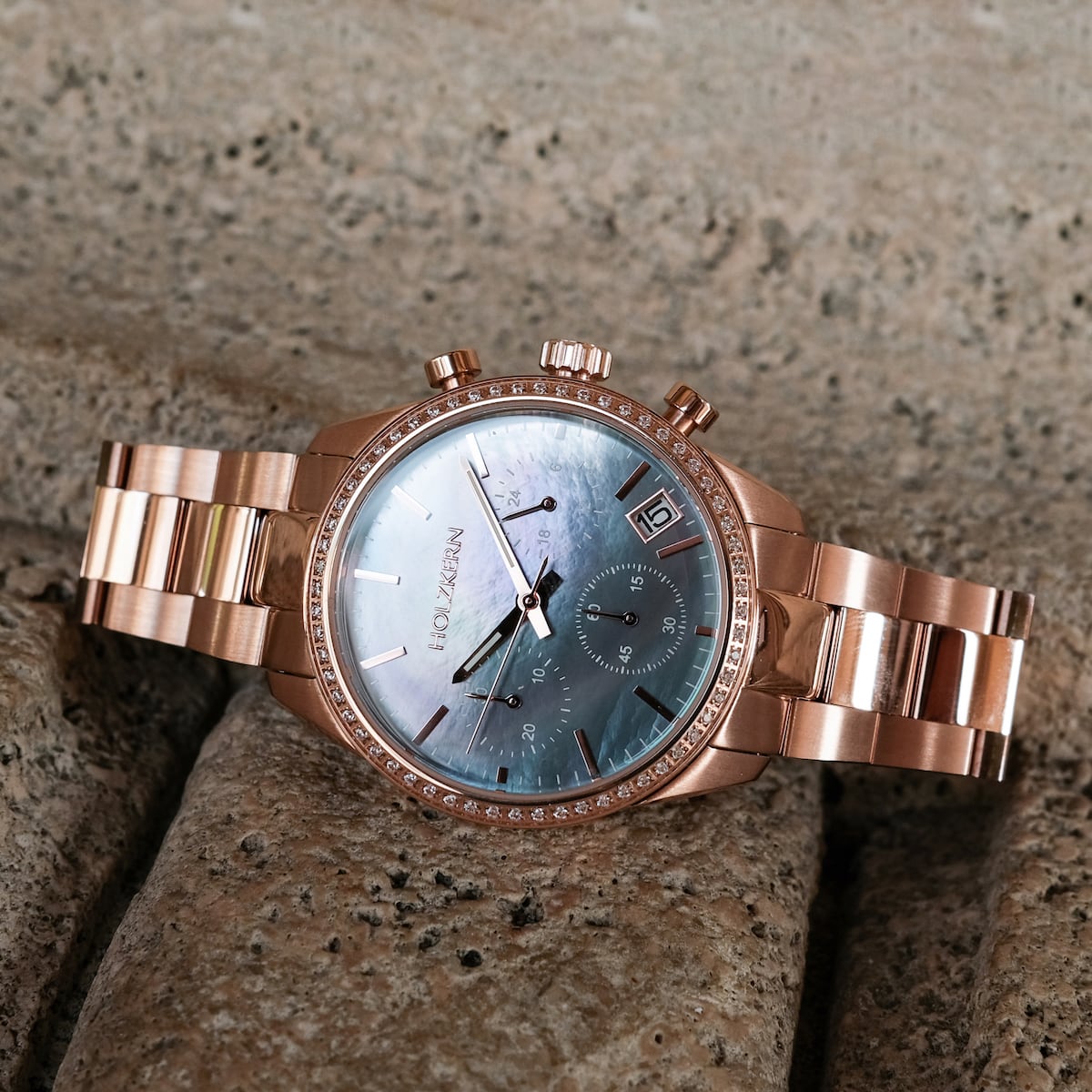 "The Passionate, a stylish watch with nacre dial and rose gold accents, displayed on textured stone surface."