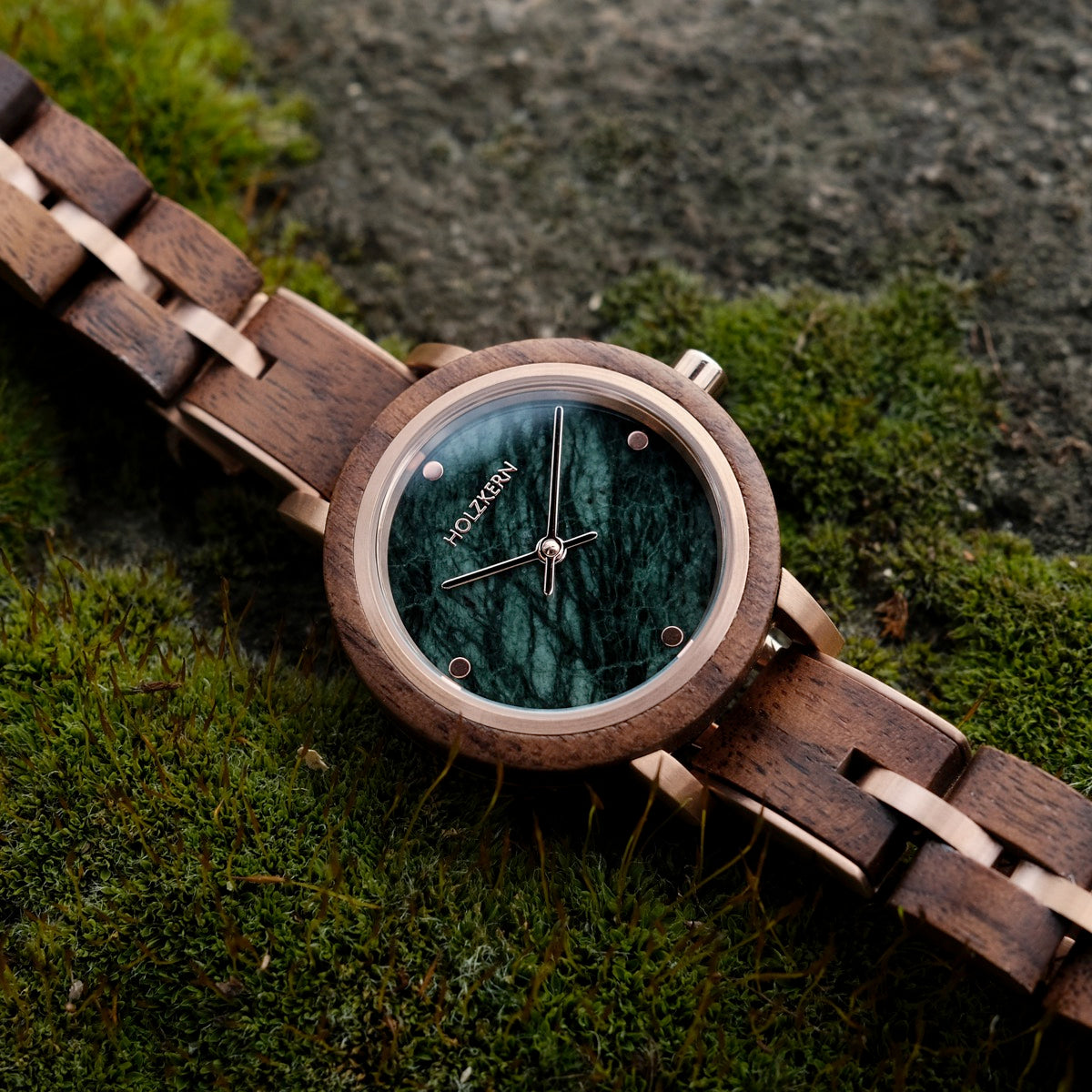 Orologio Euterpe con una banda di noci e faccia di marmo su uno sfondo mossy.