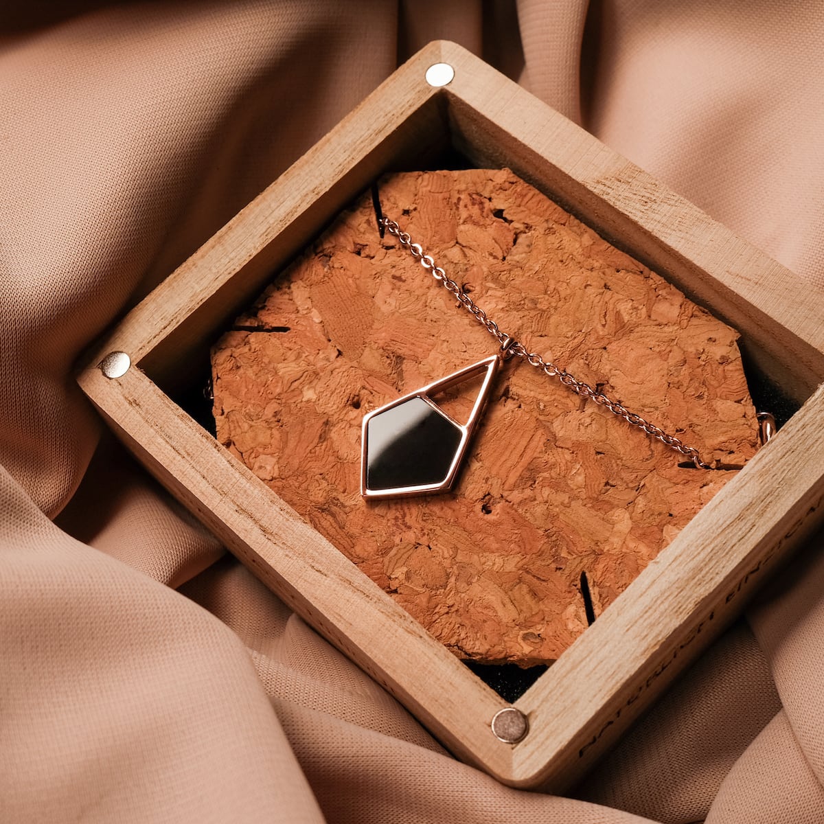 "Mandala Necklace - A marble and rose gold necklace featuring a geometric pendant, elegantly displayed in a wooden box."
